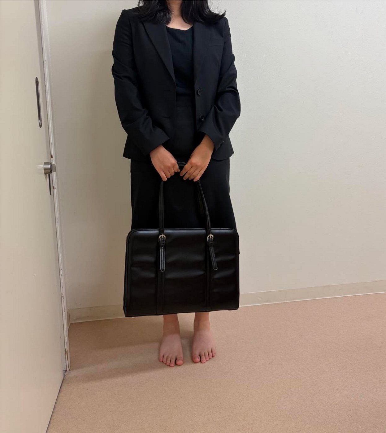 届けたスーツに袖を通した若者の後ろ姿